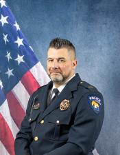 Portrait of Andrew Raatz sitting in front of an American flag
