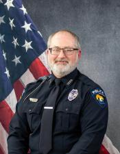 Portrait of Jason Zipperer sitting in front of an American flag