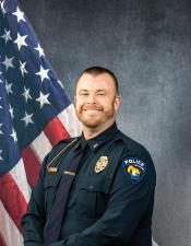 Portrait of Aaron Gauthier sitting in front of an American flag