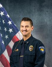 Portrait of Logan J. Tlachac sitting in front of an American flag