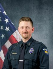 Portrait of Justin Krueger sitting in front of an American flag