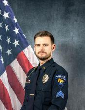 Portrait of Leander Menn sitting in front of an American flag