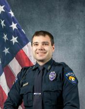 Portrait of Seth Tobison sitting in front of an American flag