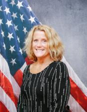 Portrait of Susan Griepentrog sitting in front of an American flag