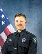 Portrait of Alek Henseler sitting in front of an American flag