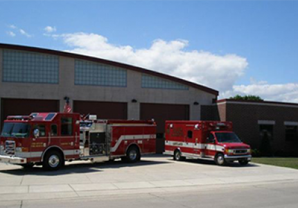 Two red fire trucks parked in front of a garage