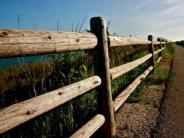 A paved path alongside a wooden post fence