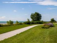 A paved path over maintained lawn and Lake Michigan in the distance