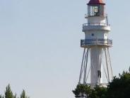 A distant view of a white lighthouse with a red top