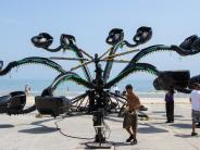 A black and teal carnival ride situated on the beach