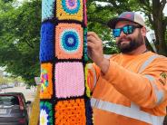 Yarn art being affixed to lamp post.