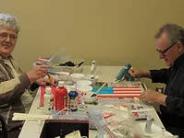 Man and woman sitting across a table from each other with craft supplies laid out