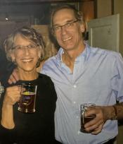 Smiling couple holding mugs of beer.
