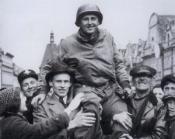 a black and white photo of Lt. Col. Konop hoisted on the shoulders of a group of men