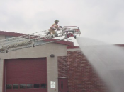 Firefighter on a ladder spraying water down below
