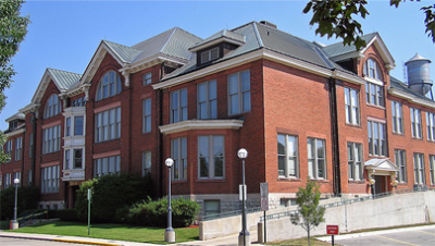 City hall picture taken from an angle showing two sides. Building is red brick with a green grass lawn out front