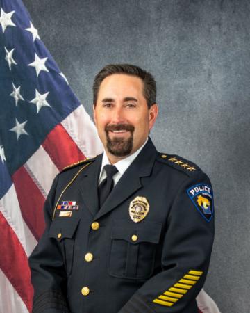 Portrait of Benjamin Meinnert sitting in front of an American flag