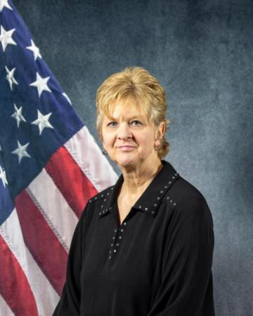 Portrait of Katheryn Schroeder sitting in front of an American flag