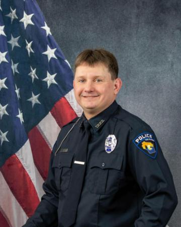 Portrait of Cale Beyer sitting in front of an American flag