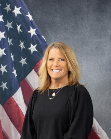 Portrait of Susan Griepentrog sitting in front of an American flag