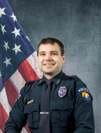 Portrait of Seth Tobison sitting in front of an American flag