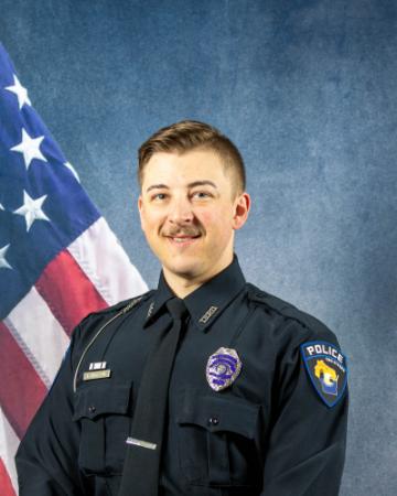 Portrait of Alek Henseler sitting in front of an American flag