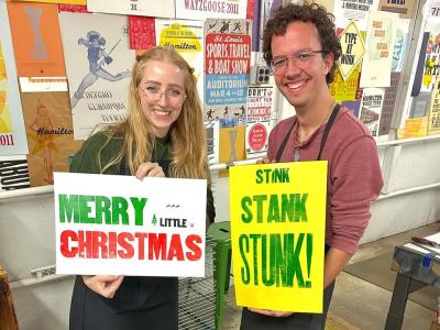 Man and woman holding colorful printed posters.