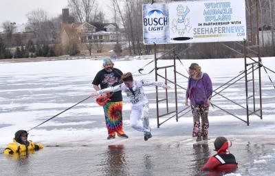 A young man jumping into the icy surface of water.