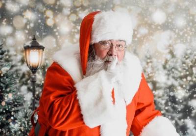 Santa with finger to lips in a "shushing" motion.