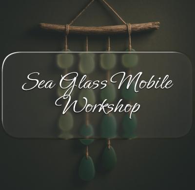 A mobile made with a stick and sea glass.