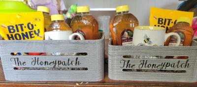 Two crates filled with honey, Bit o' Honey candy and mugs with bees.