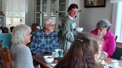 Diners being served by a woman in period dress.