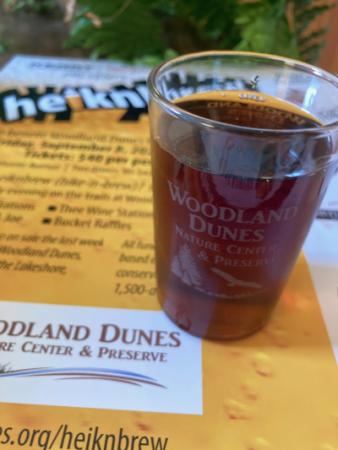 Cup of craft beer sitting atop a heiknbrew event poster.