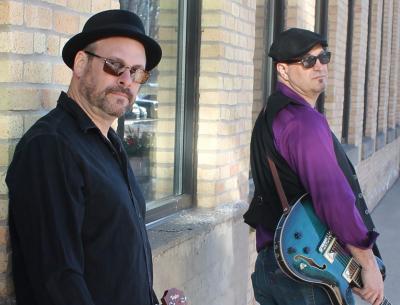 Two men in hats, one holding a guitar.