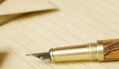 Pen on paper with documents in the background.
