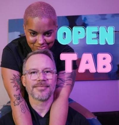 Woman standing behind seated man with her arms resting around his neck.