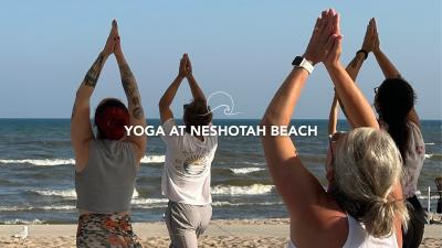 Four people holding a yoga pose and turned toward the incoming surf.