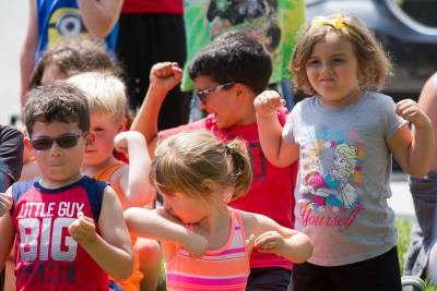 Kids outdoors flexing their biceps.