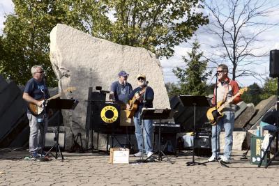 Members of Acme Pickers standin on an outdoor stage.