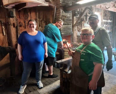 Family and instructor in blacksmithing shop at Pinecrest.