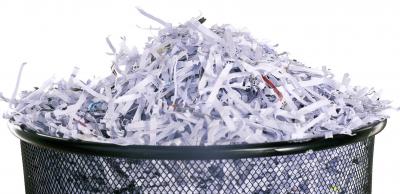 A metal wastebasket containing shredded paper.
