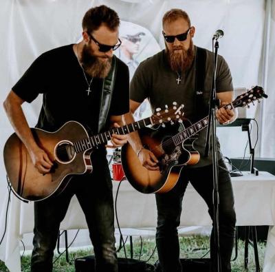 Two bearded men wearing sunglasses playing guitars onstage.