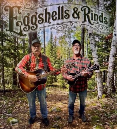 Two men in flannel shirts holding stinged instruments in the woods.
