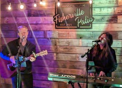Man playing guitar and woman on keyboard performing onstage.
