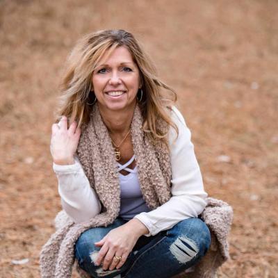 Smiling woman kneeling outdoors.