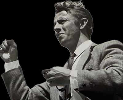 B/W photo of man in suit conducting.