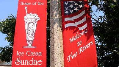 Two red pole banners, one that says Welcome to Two Rivers, the other says Home of the Ice Cream Sundae