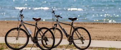 Two bikes parked at beach with lake in background.