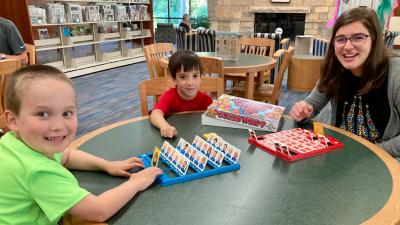 A family of a woman and two young boys playing a game in Lester Public Library
