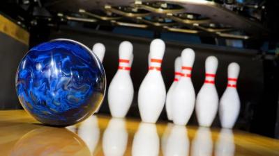 Blue bowling ball rolling toward pins.